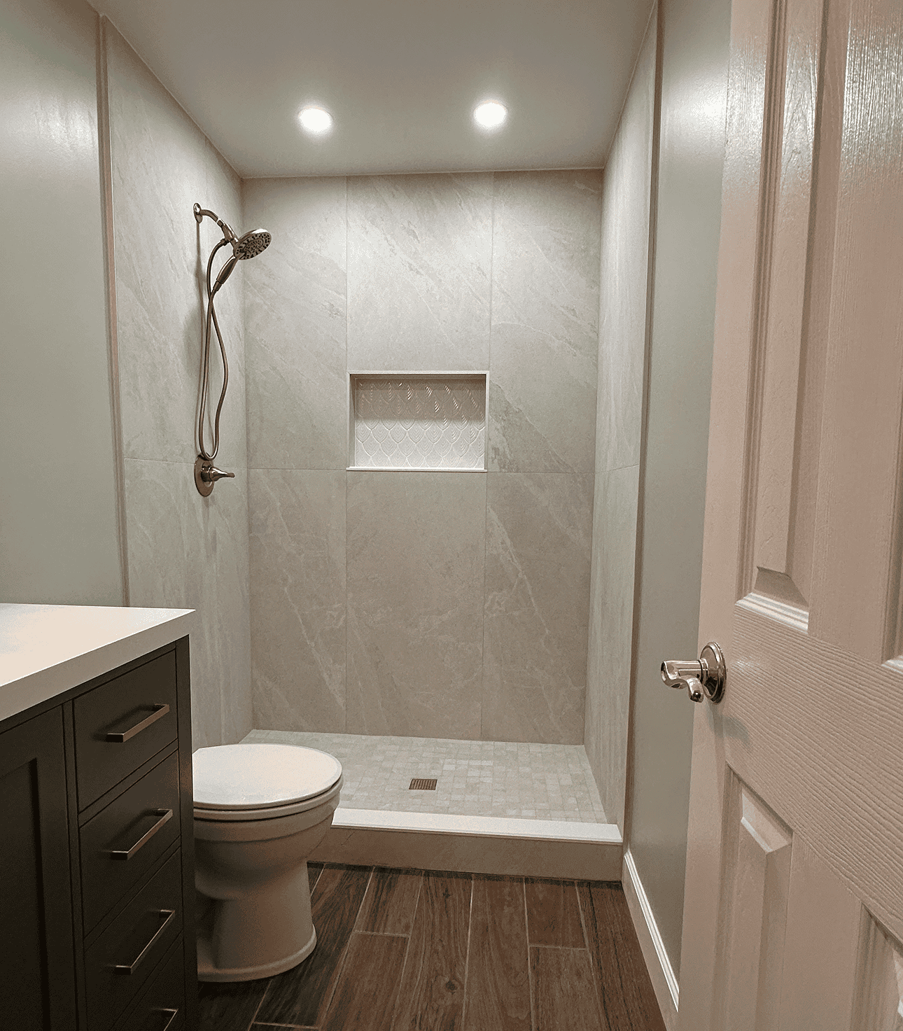 Spacious walk-in shower with beige tiles and built-in niche for toiletries.