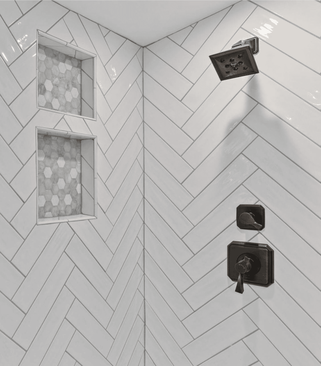 Contemporary shower with white herringbone tiles and black fixtures.